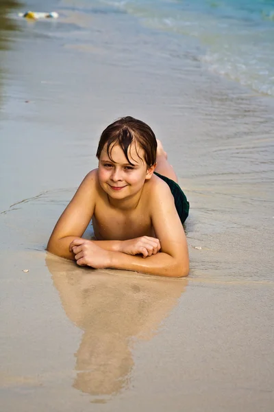 Młody chłopak jest leżąc na plaży i korzystających ciepło z — Zdjęcie stockowe