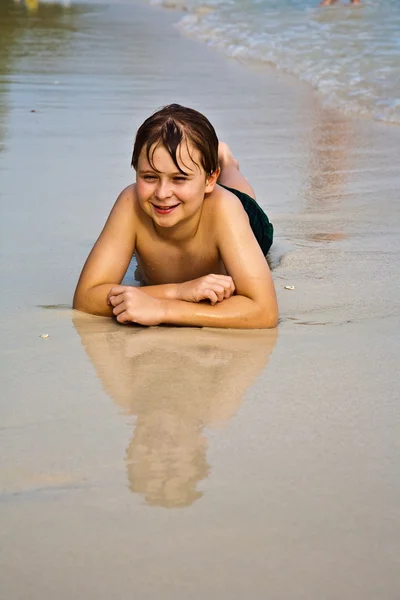 Jeune garçon est allongé à la plage et profiter de la chaleur de la — Photo