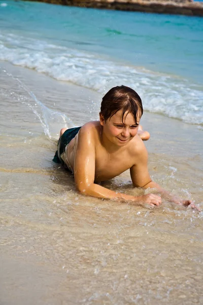 Ung pojke ligger på stranden och njuter warmness av den — Stockfoto