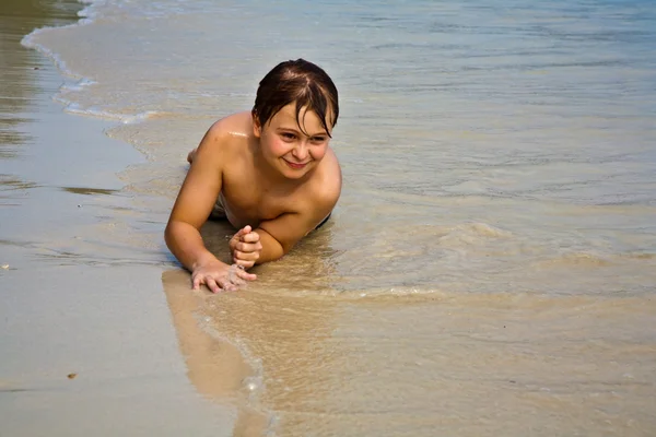 Kleiner Junge liegt am Strand und genießt die Wärme der Sonne — Stockfoto