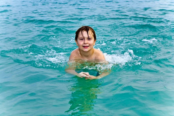 Fiatal fiú a meleg, kristálytiszta tenger úszás és élvezi a vac — Stock Fotó