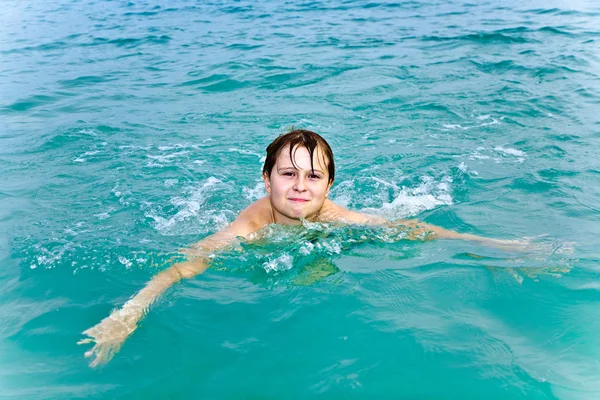 Молодий хлопчик плаває в теплому чистому морі і насолоджується відпочинком — стокове фото