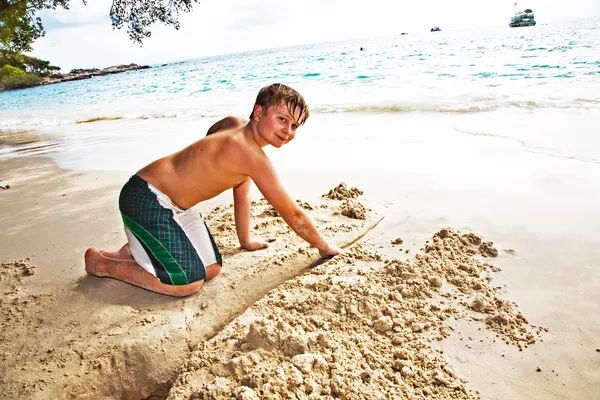 Ευτυχισμένο αγόρι να χτίσει μια διώρυγα από άμμο στο bea — Φωτογραφία Αρχείου