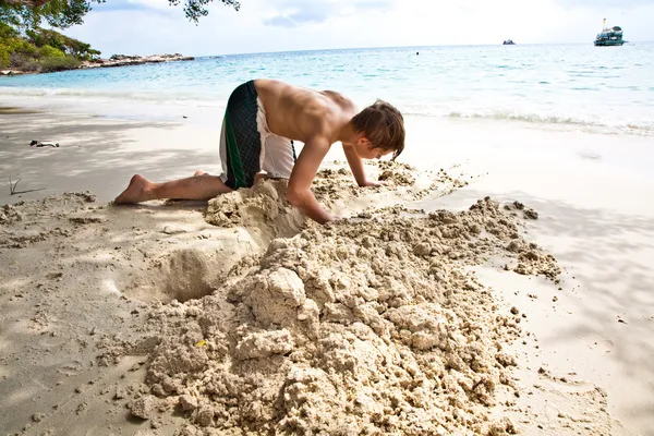 幸せな少年は、bea で砂から運河を構築します。 — ストック写真
