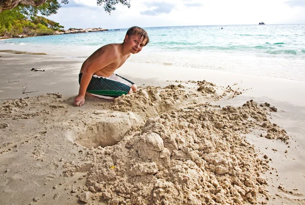 Menino feliz está construindo um canal a partir de areia no bea — Fotografia de Stock