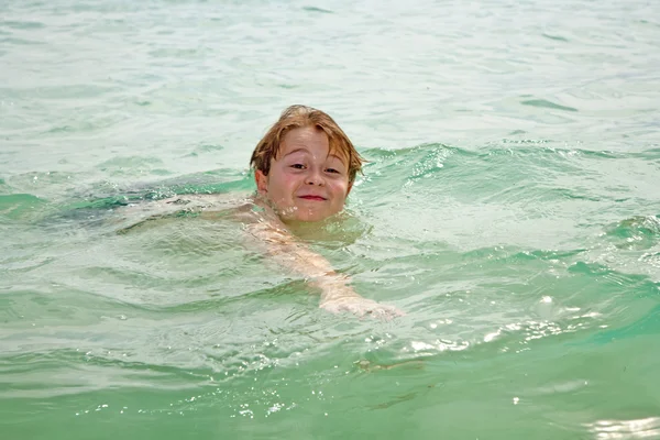 Kleiner glücklicher Junge mit braunen Haaren genießt das Schwimmen in der schönen — Stockfoto