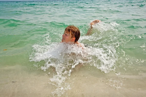 Jovem menino feliz com cabelo castanho gosta de nadar na bela — Fotografia de Stock