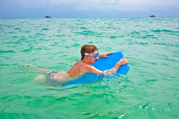 Молодой счастливый мальчик с каштановыми волосами наслаждается плаванием в красивой — стоковое фото