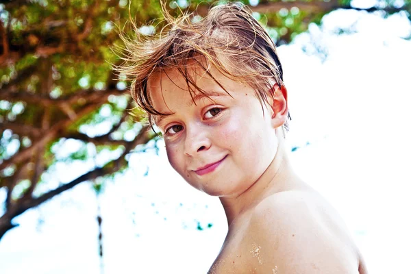 Młody chłopak na plaży jest uśmiechnięty i szuka siebie — Zdjęcie stockowe