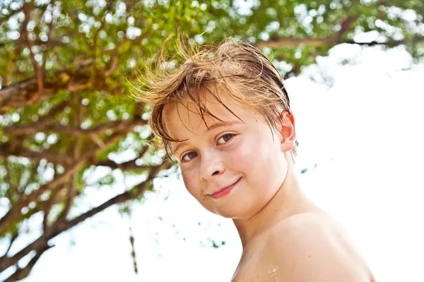 Jonge jongen op het strand is glimlachend en zelf vertrouwen op zoek — Stockfoto