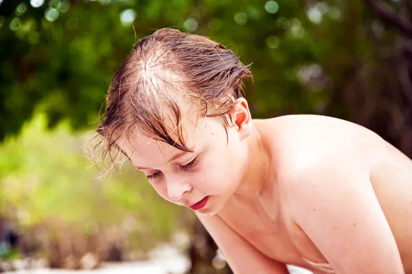 Kleiner Junge mit nassen Haaren kommt lächelnd aus dem Meer und sieht aus — Stockfoto