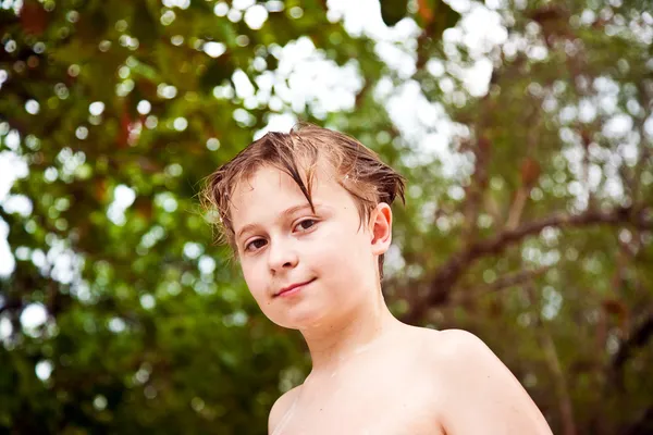 Молодий хлопчик з мокрим волоссям виходить з моря посміхаючись і виглядає — стокове фото