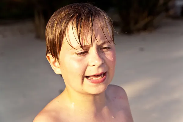 Angry young boy with wet face at the beautiful sandy beach — Stock Photo, Image