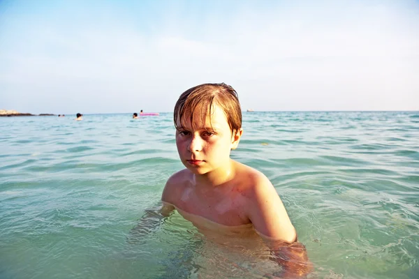 Angry young boy is walking thru the clear warm saltwater at the — Stock Photo, Image