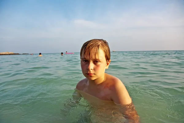 Boos jongen loopt via de duidelijke warm zout water op de — Stockfoto