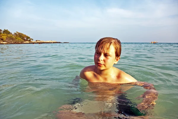 Arrabbiato giovane ragazzo sta camminando attraverso la chiara acqua salata calda al — Foto Stock