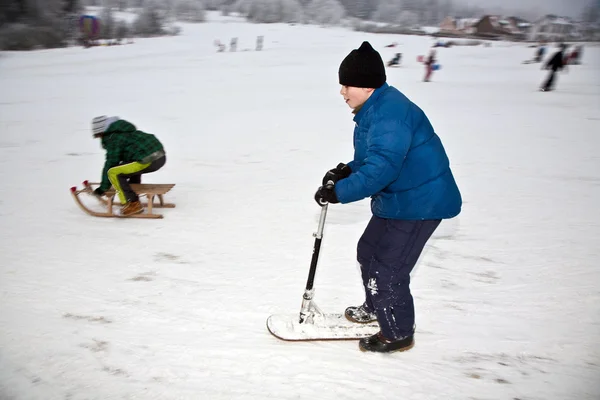 Los niños están patinando en una carrera de trineo en invierno en la nieve — Foto de Stock