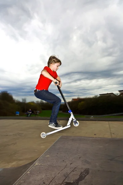 Menino montando uma scooter está pulando em um parque de scooter — Fotografia de Stock