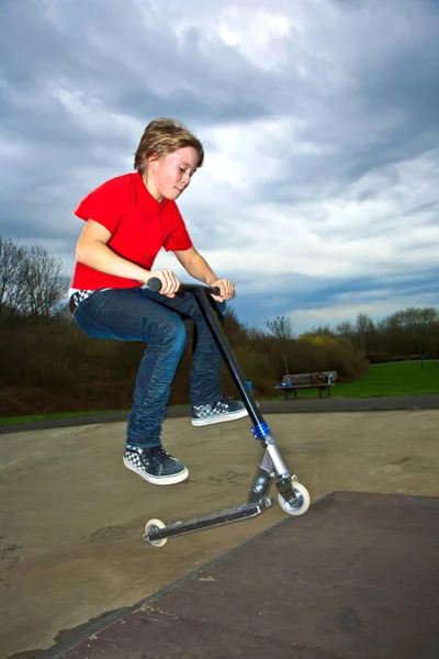 Menino montando uma scooter está pulando em um parque de scooter — Fotografia de Stock