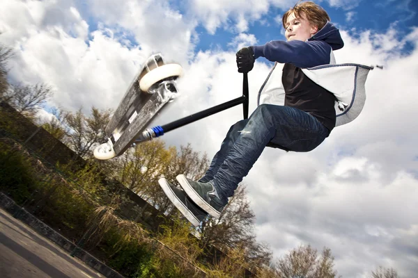 Мальчику весело летать по воздуху на скутере — стоковое фото
