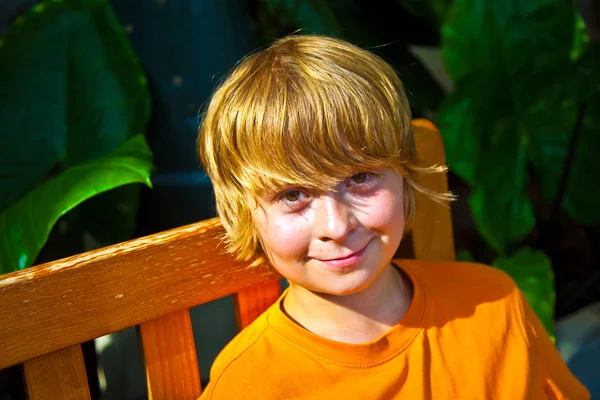Boy relaxing on a bench in the botanical garden — Stock Photo, Image