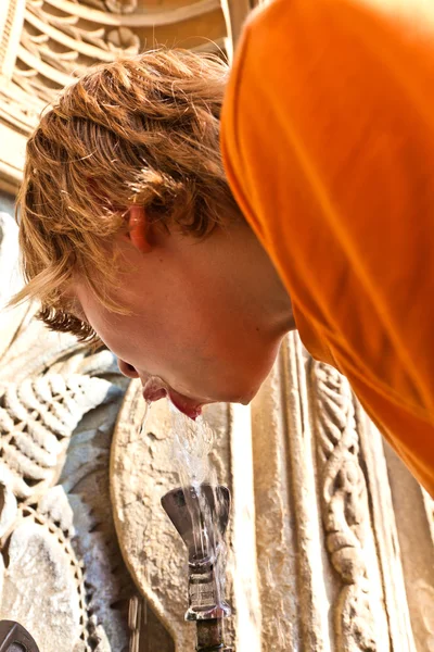 Мальчик пьет воду на общественном фонтане — стоковое фото