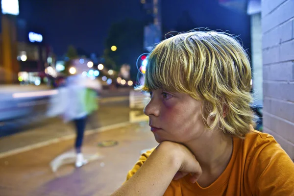 Söt pojke ler trött när han satt utanför på natten — Stockfoto