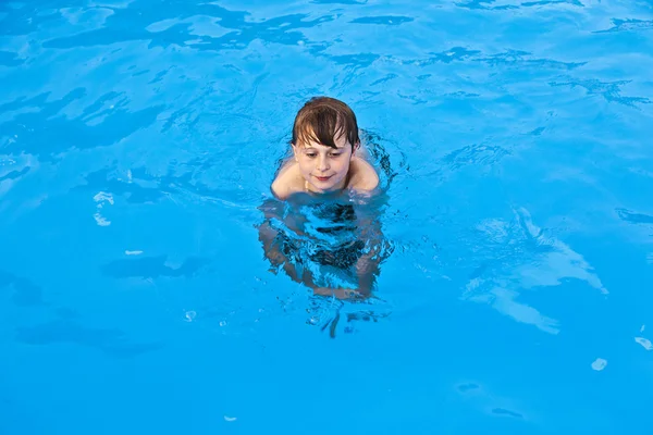 Мальчик весело плавает в бассейне — стоковое фото