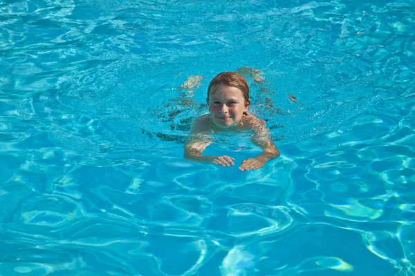 Criança nada na piscina e se diverte — Fotografia de Stock