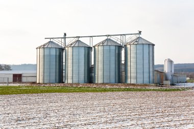 Acres with snow in winter with silo in beautiful light and struc clipart