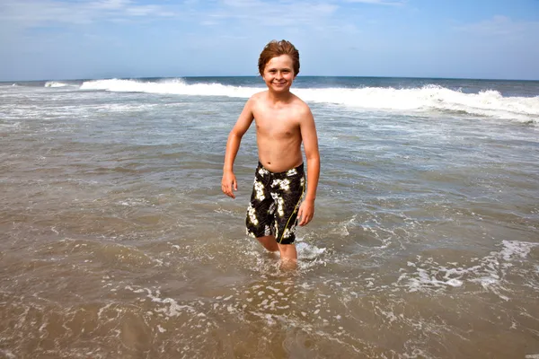 Ładny chłopak ma zabawy w burzliwy beach — Zdjęcie stockowe