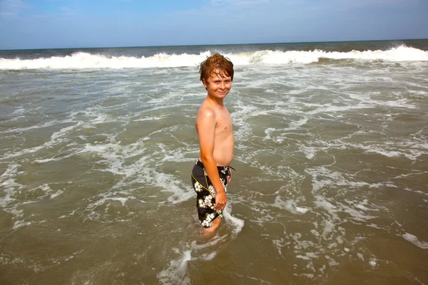 Roztomilý chlapec má zábavu v bouřlivé beach — Stock fotografie