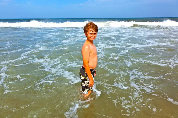 Menino bonito tem diversão na praia tempestuosa — Fotografia de Stock