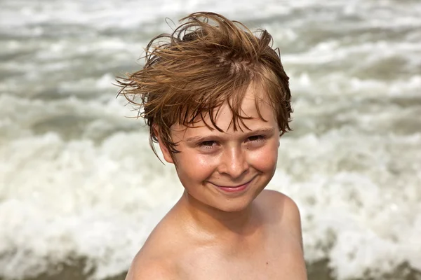 Милий хлопчик розважається на штормовому пляжі — стокове фото