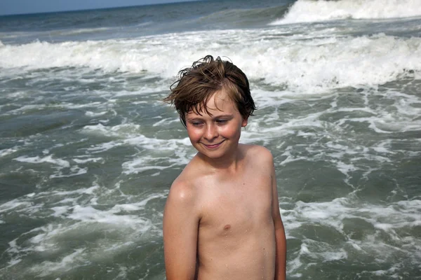 Netter Junge hat Spaß am stürmischen Strand — Stockfoto
