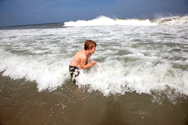 Roztomilý chlapec má zábavu v bouřlivé beach — Stock fotografie