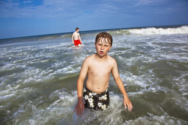 Menino bonito tem diversão na praia tempestuosa — Fotografia de Stock