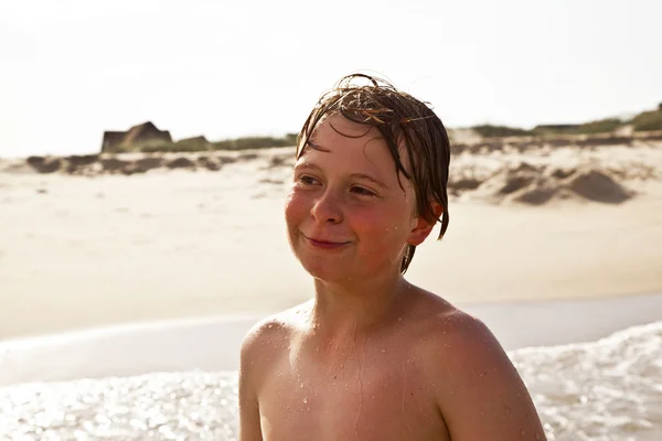 Schattige jongen heeft plezier in het stormachtige strand — Stockfoto