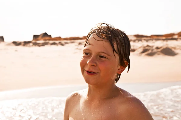 Carino ragazzo ha divertente in il tempestoso spiaggia — Foto Stock