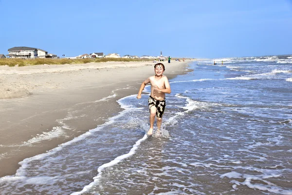 Menino corre ao longo da bela praia — Fotografia de Stock