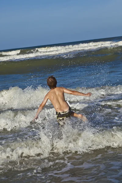 Мальчик наслаждается волнами синего моря — стоковое фото