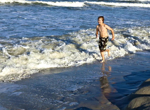 Jeune garçon jouit des vagues de la mer bleue — Photo