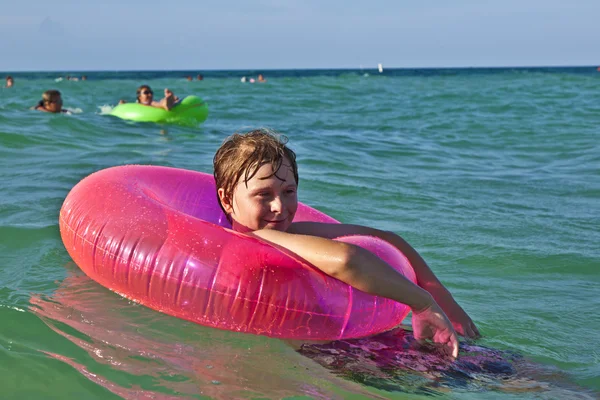Garçon dans un anneau de natation s'amuse dans l'océan — Photo