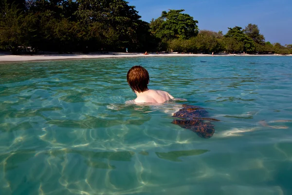 Niño con el pelo rojo está nadando en la hermosa playa cálida y clara como —  Fotos de Stock