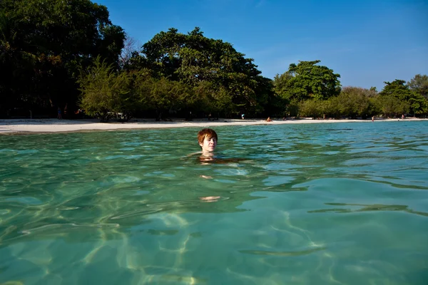 红头发的男孩在像美丽温暖清晰海滩游泳 — 图库照片