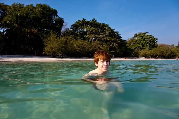 Хлопчик з рудим волоссям плаває в красивому теплому чистому пляжі, як — стокове фото