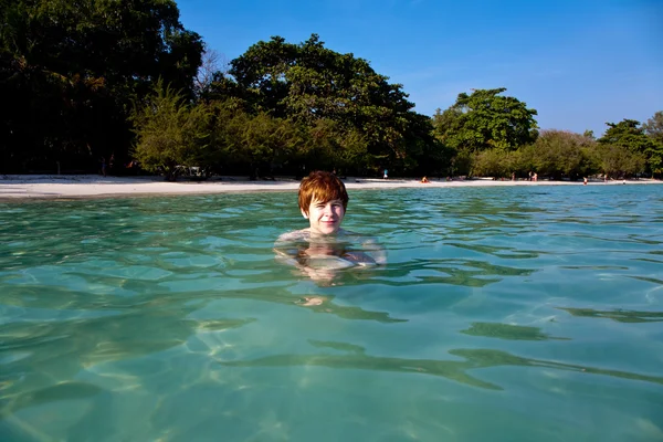 Menino com cabelo vermelho está nadando na bela praia clara quente como — Fotografia de Stock