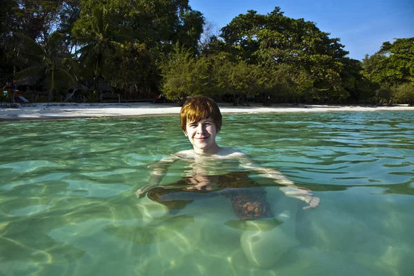 Pojke med rött hår simning i vackra varma klara strand som — Stockfoto