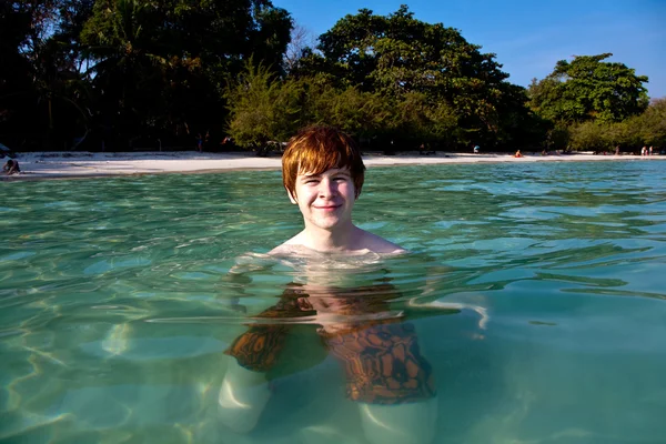 Menino de cabelos vermelhos goza da água cristalina no mar — Fotografia de Stock