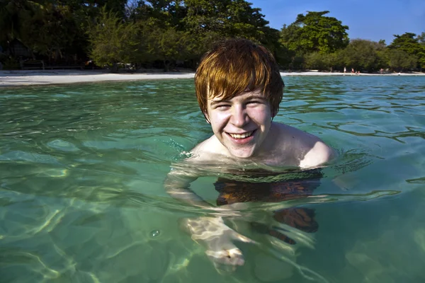 红头发的男孩喜欢水晶般清澈的水在海 — 图库照片